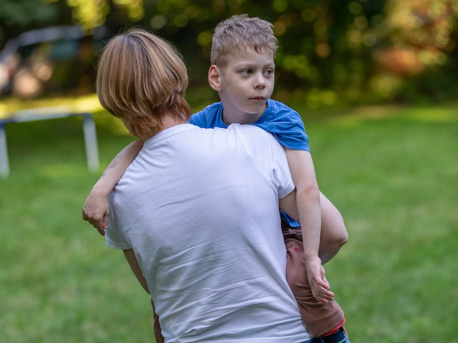 Mama neša Arnoldą ant rankų kieme